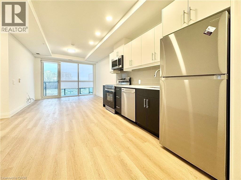 A modern kitchen with wooden floors and stainless steel appliances.