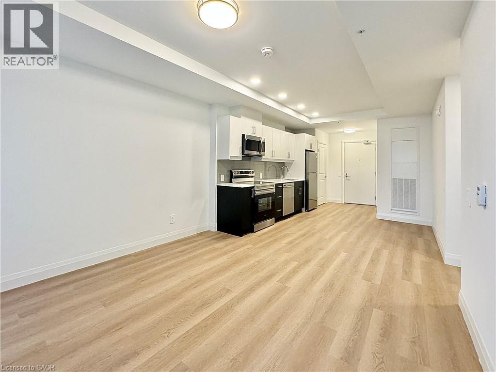 A spacious kitchen with white walls and wooden flooring.