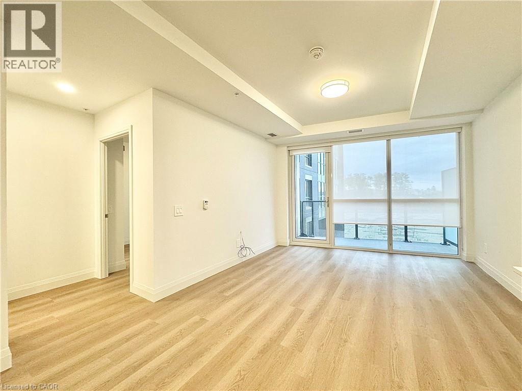 A spacious room with wooden flooring and a sliding glass door leading to a balcony.