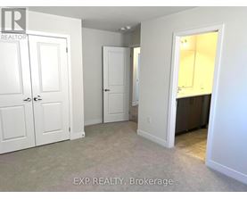 A real estate listing photo of a bedroom with white walls and carpet.