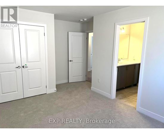A real estate listing photo of a bedroom with white walls and carpet.