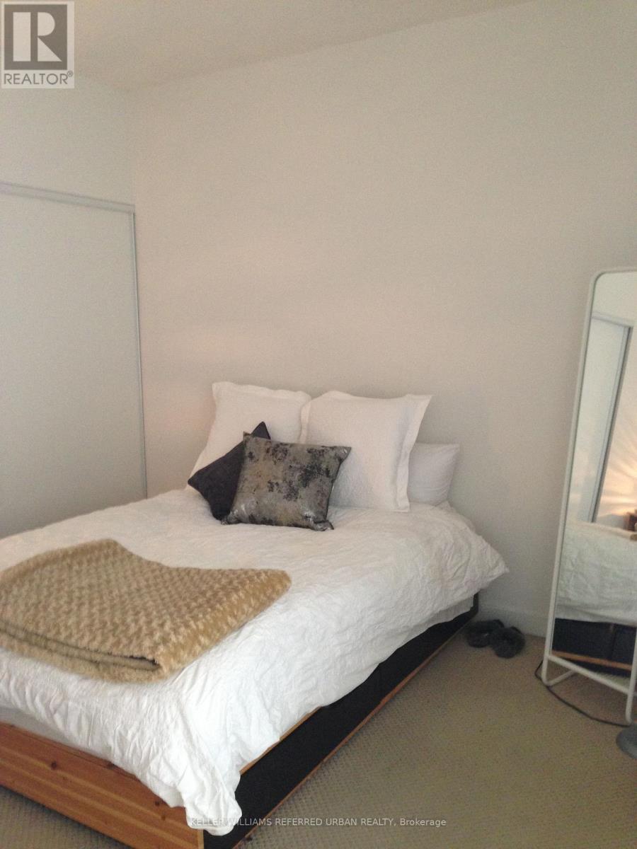A bedroom with a white bed and a brown throw.
