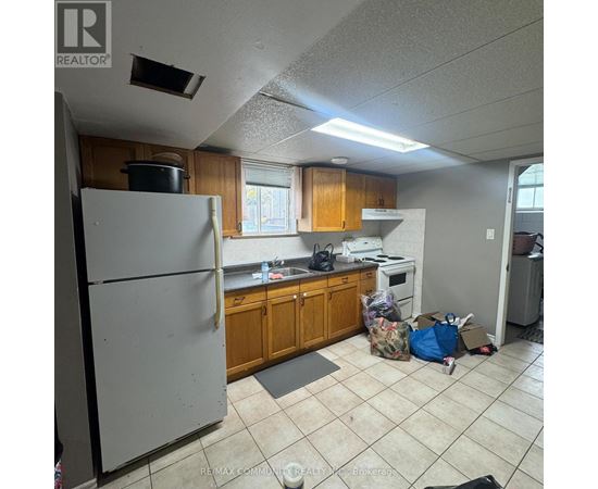 A kitchen with a refrigerator, oven, and a bag of trash on the floor.