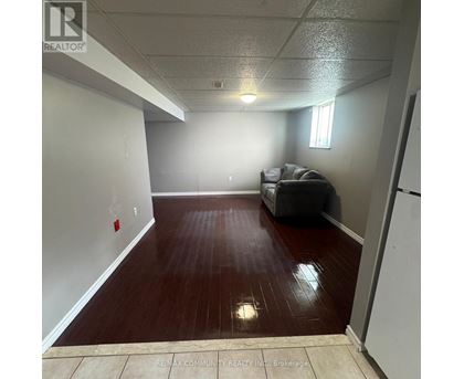 A room with a grey couch and a wooden floor.