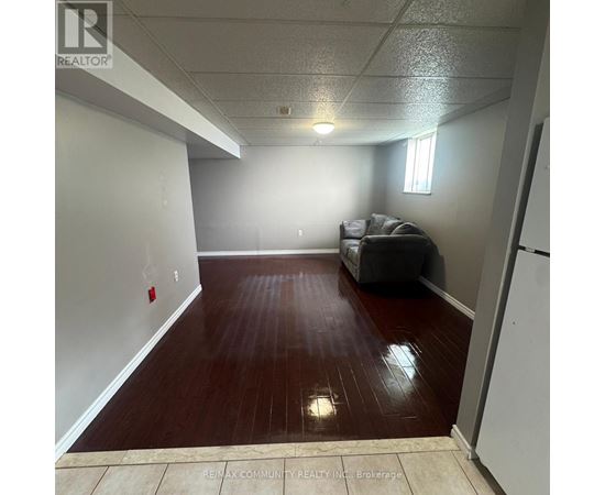 A room with a grey couch and a wooden floor.