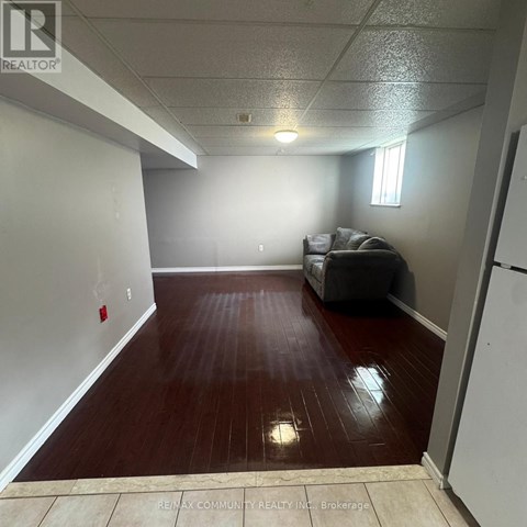 A room with a grey couch and a wooden floor.
