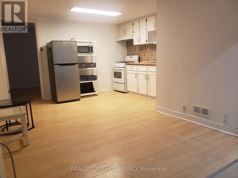 A kitchen with white appliances and wooden floors.