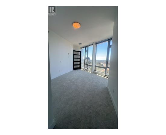 A room with a carpeted floor and a large window overlooking a cityscape.