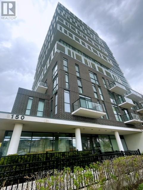A tall residential building with balconies and a black fence in front.