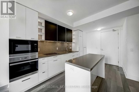 A modern kitchen with white cabinets and a black oven.