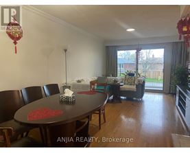 A dining room with a table and chairs and a sofa in the background.