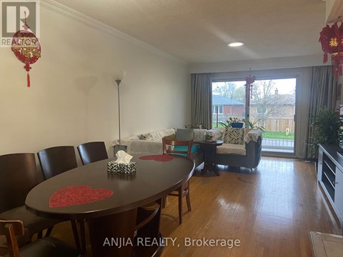 A dining room with a table and chairs and a sofa in the background.