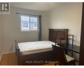 A bedroom with a bed, chair, and window.