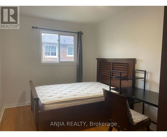A bedroom with a bed, chair, and window.