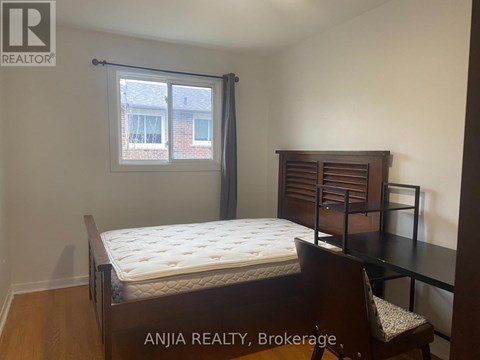 A bedroom with a bed, chair, and window.