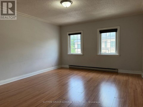 A room with wooden floors and two windows.