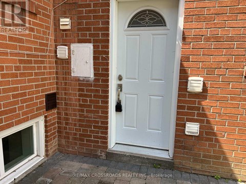 A white door with a glass window above it is set in a brick wall.