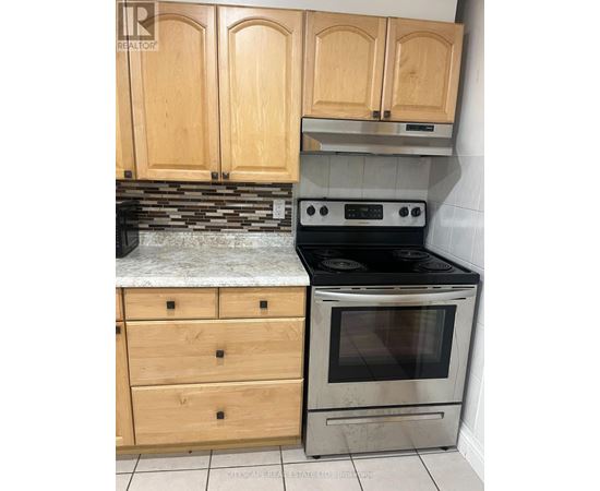 A kitchen with wooden cabinets and a stove top oven.