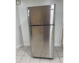 A silver fridge with a white door is in a room.
