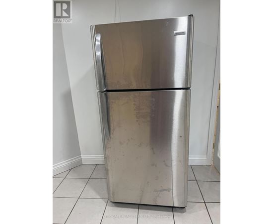 A silver fridge with a white door is in a room.