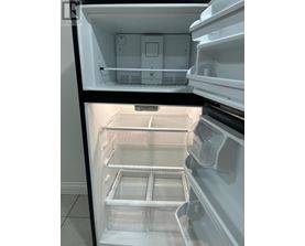 A white refrigerator with the door open showing the empty shelves.