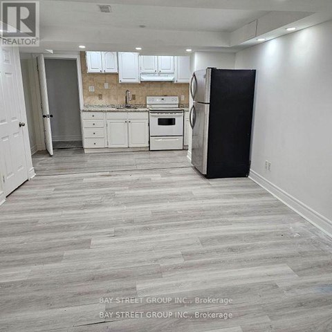 A kitchen with white cabinets and a black refrigerator.