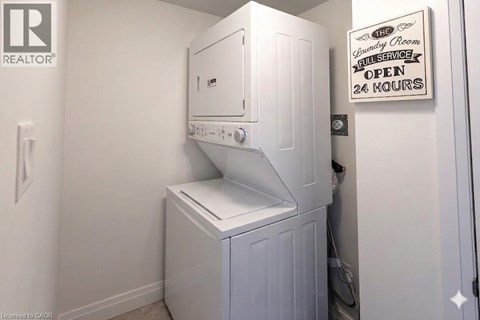 A washing machine is in a small room with a sign that says open 24 hours.