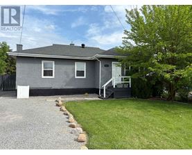 A grey house with a gravel driveway in front.