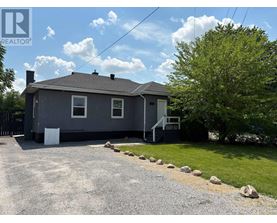 A house with a grey roof and a gravel driveway in front.