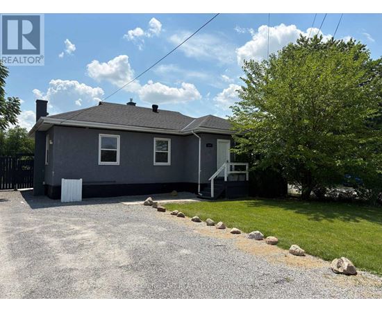 A house with a grey roof and a gravel driveway in front.