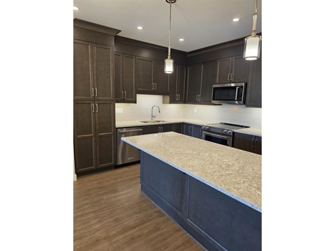 A kitchen with dark brown cabinets and a light countertop.