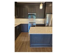 A kitchen with a stove top oven and a refrigerator.