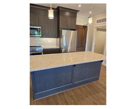A kitchen with a granite countertop and dark cabinets.
