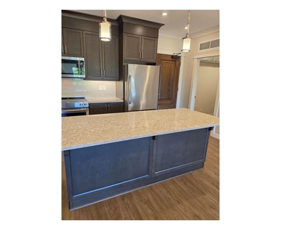 A kitchen with a granite countertop and dark cabinets.