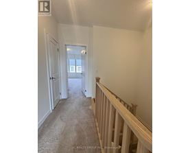 A hallway with a carpeted floor and white walls.