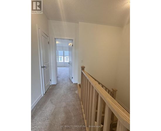 A hallway with a carpeted floor and white walls.