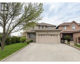 A two-story house with a garage is surrounded by a well-maintained lawn and trees.