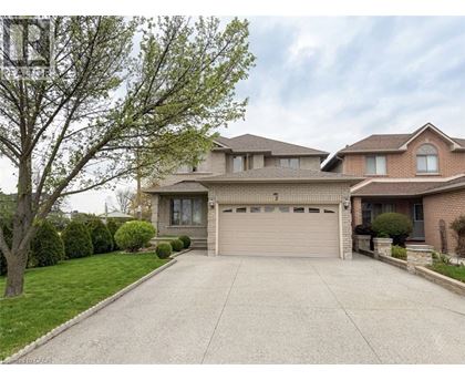 A two-story house with a garage is surrounded by a well-maintained lawn and trees.