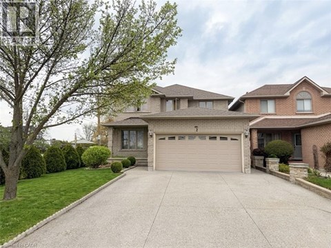 A two-story house with a garage is surrounded by a well-maintained lawn and trees.