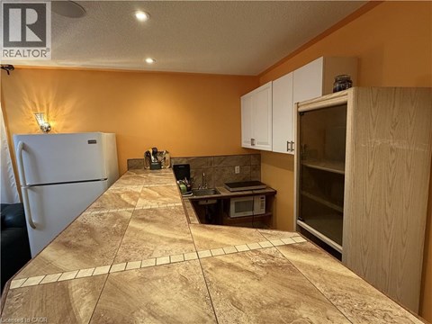 A kitchen with a refrigerator, microwave, and oven.