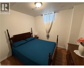 A bedroom with a bed, nightstand, and a window with a blue curtain.
