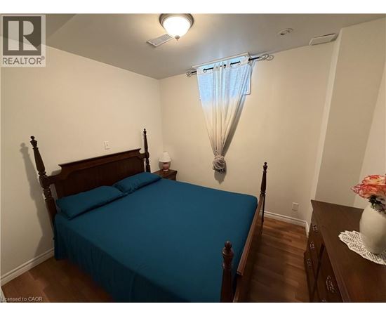 A bedroom with a bed, nightstand, and a window with a blue curtain.