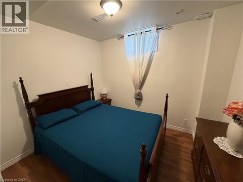 A bedroom with a bed, nightstand, and a window with a blue curtain.