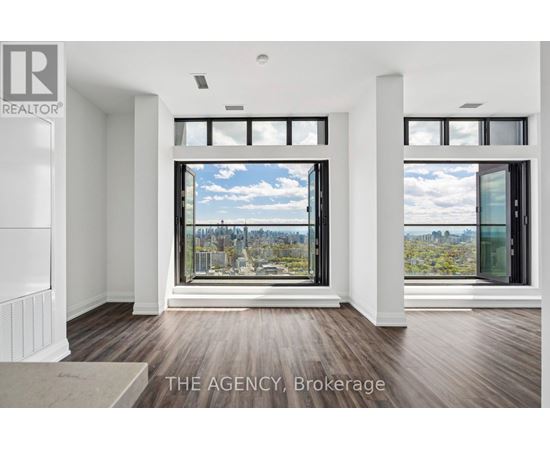 A real estate agency showcases a spacious room with a view of the cityscape through large windows.
