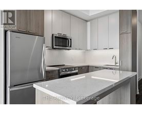A modern kitchen with a stainless steel refrigerator and a microwave above the counter.