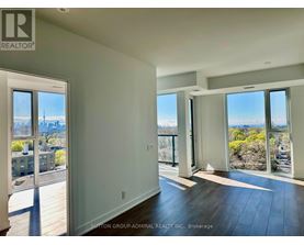 A spacious room with a view of the cityscape through large windows.