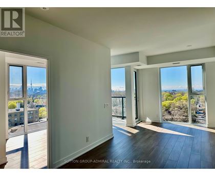 A spacious room with a view of the cityscape through large windows.