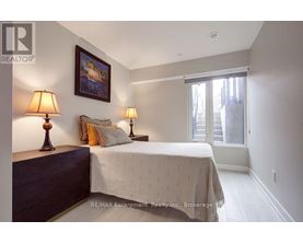 A bedroom with a bed, two lamps, and a painting on the wall.