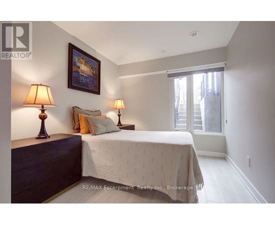 A bedroom with a bed, two lamps, and a painting on the wall.