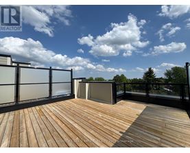 A wooden deck with a glass railing and a hot tub on a sunny day.